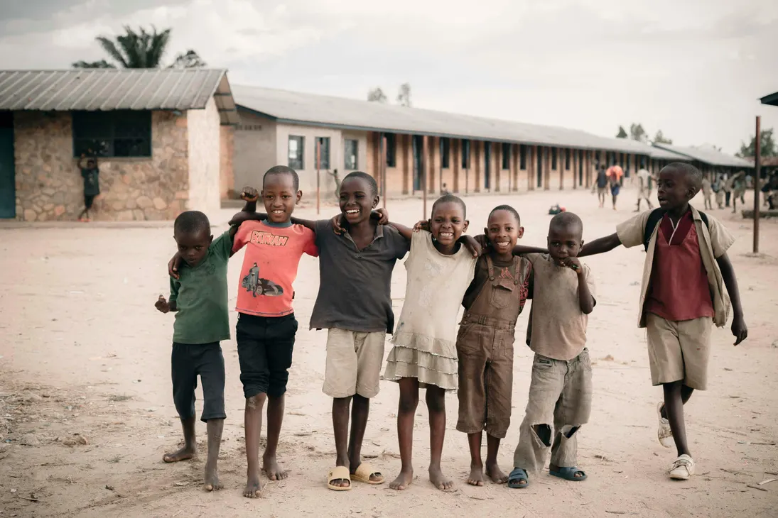 A group of smiling children standing arm in arm outside a school building