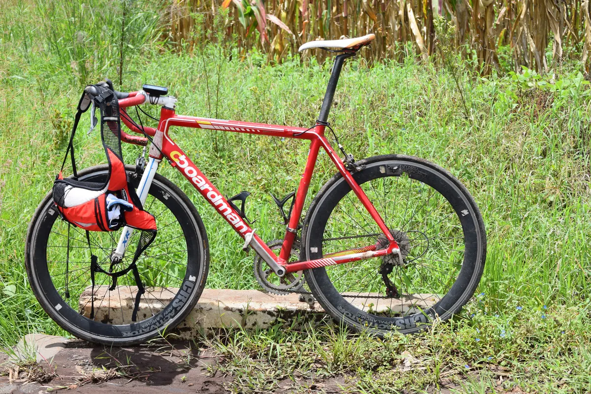 A red road bicycle standing in tall green grass
